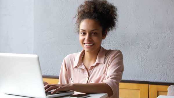 Smiling young black woman working on laptop